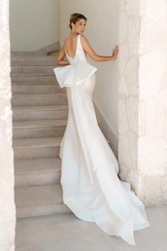 a woman in a white dress is standing on some stairs