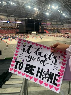 someone holding up a sign that says it's good to be home at a sporting event