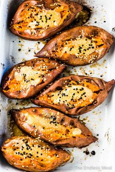 baked sweet potatoes in a baking pan with sesame seeds and seasoning sprinkled on top