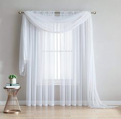 a living room with white curtains and a table