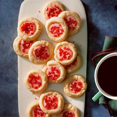 small cookies with jam are on a platter next to a cup of coffee and napkin