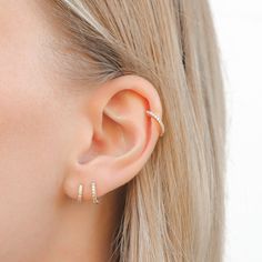 a close up of a woman's ear with two small diamond hoops on it