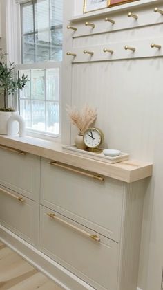 a kitchen with white cabinets and gold handles on the countertop, next to a window