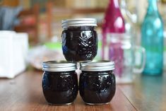 four jars filled with jam sitting on top of a wooden table