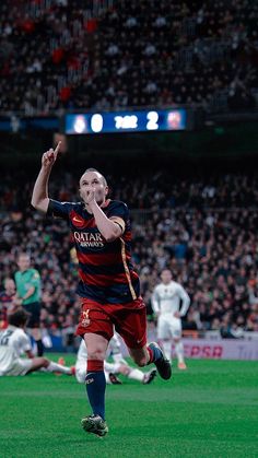 a soccer player is running on the field with his arms in the air as he celebrates