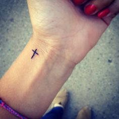 a woman's wrist with a cross tattoo on it