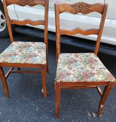 two wooden chairs sitting next to each other on a parking lot in front of a white van