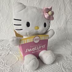 a hello kitty stuffed animal holding a small pink box with the word smalfy written on it