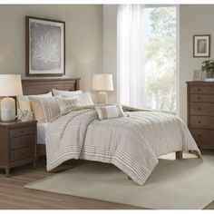 a bed in a bedroom with white and beige comforter set on top of it