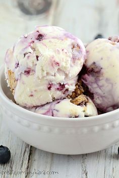 two scoops of ice cream in a bowl with blueberries