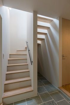 an empty room with stairs leading up to the second floor and light coming in from above