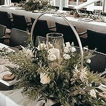 an arrangement of flowers and greenery on a table in a restaurant or dining room