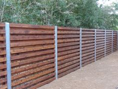 a wooden fence is lined with metal posts