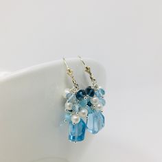 One of a kind Blue Topaz Cluster Earrings, are a perfect way to add a burst of color to any outfit. The fabulous array of colored gems include Sky Blue Topaz, Larimar, London Blue Topaz and Small Freshwater Pearls. This beautiful bouquet of gems sits on top of a unique asymmetrical large Sky Blue Topaz gemstone. Sterling Silver findings, lever back Earwires with a 2 inch drop length. Each set is personally handcrafted , so no two sets are identical. Handmade and designed in Stuart, FL and shipped from the US * In order to create unique and distinctive pieces, I use diverse shapes of natural gems to ensure that no two pieces are exactly the same. As such, each gem in hand-picked and inspected to ensure quality. However, I cannot create exact replications of any piece due to the natural vari Blue Topaz Earrings With Gemstone Accents, Blue Briolette Earrings Fine Jewelry, Fine Jewelry Blue Topaz Earrings With Gemstone Accents, Blue Faceted Drop Earrings, Fine Jewelry Blue Topaz Drop Earrings, Blue Topaz Drop Earrings Fine Jewelry, Light Blue Topaz Drop Earrings, Light Blue Blue Topaz Drop Earrings, Elegant Blue Faceted Crystal Earrings