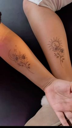 two women with matching tattoos on their arms, one holding the other's hand