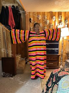 a woman standing in a room with her arms spread out and wearing a colorful dress