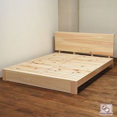 a wooden bed frame sitting on top of a hard wood floor next to a white wall