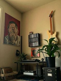 a living room with a guitar, plant and other items on the wall in front of it