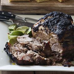 a piece of meat on a white plate with limes