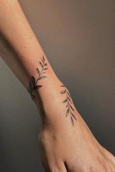 a woman's hand with a small tattoo on the wrist and an olive branch