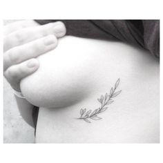 a woman's stomach with a small branch tattoo on it