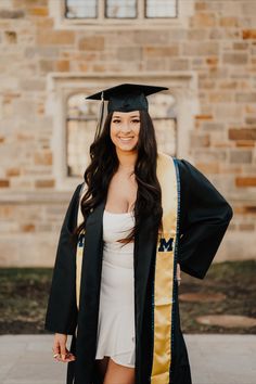 a woman in a graduation gown and cap posing for a photo with her hands on her hips