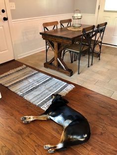 a black and brown dog laying on top of a wooden floor next to a table