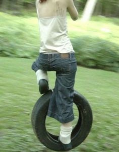 a woman riding on top of a tire in the grass