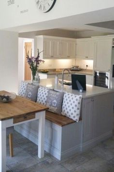 a kitchen with a table and two benches in front of the counter top that has a clock on it