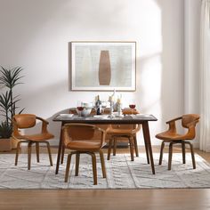 a dining room table with chairs and an art piece on the wall above it, in front of a potted plant