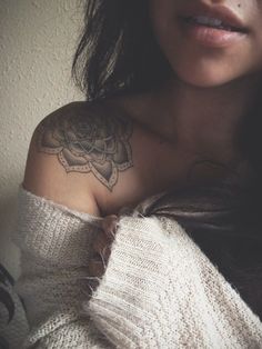 a woman's arm with a tattoo on it and a sweater over her shoulder