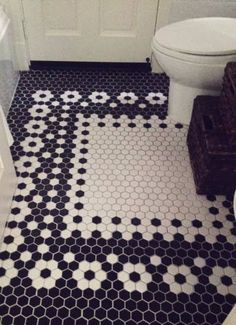 a bathroom with black and white hexagonal tiles on the floor, toilet and sink