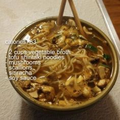 a bowl filled with noodles and vegetables on top of a table