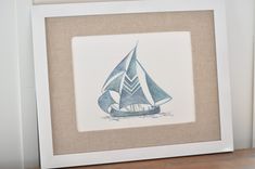 a watercolor painting of a sailboat in blue and white, on a shelf