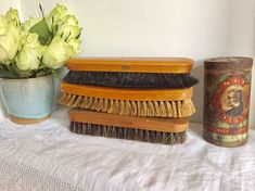 three brushes are sitting on a table next to a vase with white flowers in it