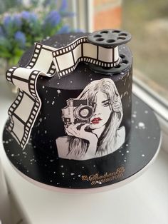 a black and white cake with a woman holding a camera on the top of it