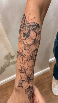 a woman's arm with flowers and a butterfly on it