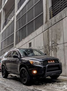 a black toyota rav parked on the side of a road next to a building