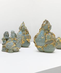 three ceramic figurines sitting next to each other on a white counter top with gold accents