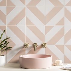 a pink sink sitting next to a potted plant on top of a white counter