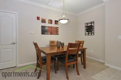 a dining room table with four chairs and pictures on the wall above it in an apartment