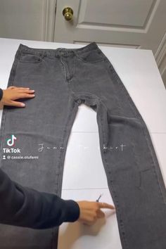 someone is cutting out the bottom part of a pair of jeans