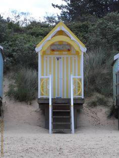 a yellow and white lifeguard hut on the beach