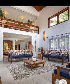 a living room with blue couches and wooden tables in front of the windows on the second floor