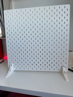 a white computer desk with a red light on it's side and a laptop in the background