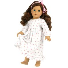 a doll with brown hair wearing a white dress and pink bow in her hair is standing