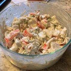 a glass bowl filled with chicken salad sitting on top of a counter next to a knife