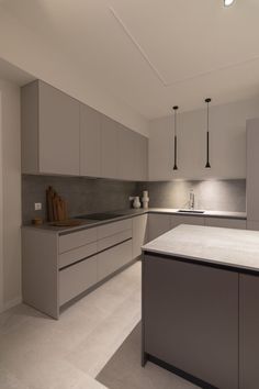 an empty kitchen with white cabinets and gray counter tops is seen in this image from the front view