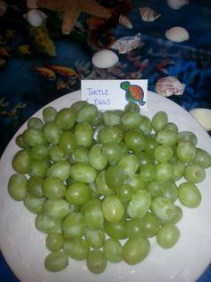 grapes are on a plate with a little sign in front of them that says little eggs