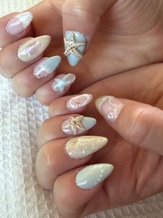 a woman's hands with some white and silver nail polishes on their nails